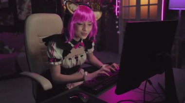 Kedi kulaklı şirin kıyafetler giyen, oyun oynayan, gazlı içeceğini yudumlayan ve canlı yayında takipçilerle konuşan genç bayan Cosplayer.