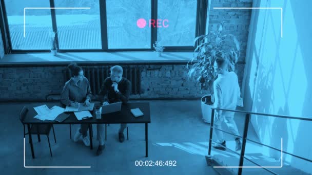 监视摄像头拍摄的是男人和女人坐在阁楼办公室的办公桌前一起工作的情景 他们的同事帮助他们修理一些东西 — 图库视频影像