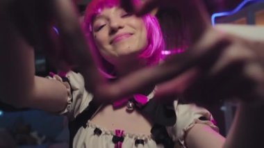 Kamerada pembe peruk ve neko kulaklı neşeli Z kadın Cosplayer 'ın orta boy yakın plan portresi.