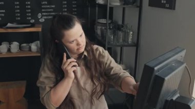 Engelli bir kadının telefon görüşmesinde müşteriden sipariş alırken yüksek açılı çekimleri.