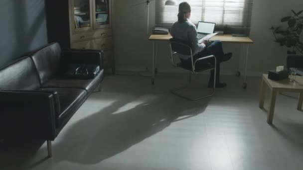 一个无法辨认的男性心理治疗师坐在办公室的办公桌前准备赴约 他的视角很远 — 图库视频影像