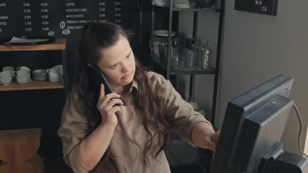 小さな喫茶店で働く障害のある若い白人女性のHighアングルショットは 電話で顧客から注文を得る — ストック動画