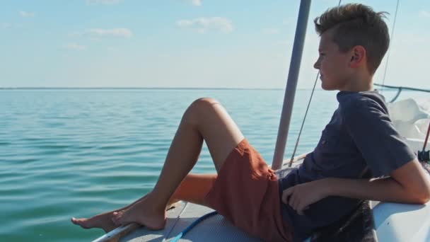 Кавказский Подросток Сидит Расслабленный Борту Яхты Наслаждаясь Солнечным Летним Днем — стоковое видео