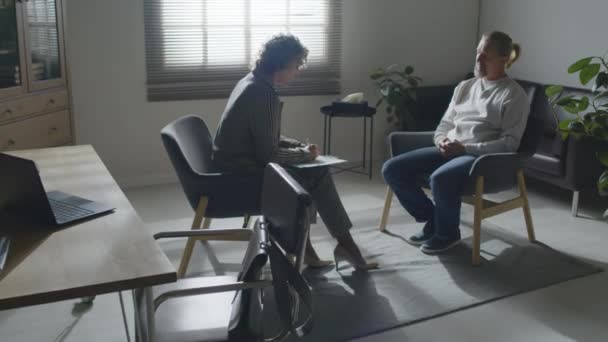 Długie Ujęcie Współczesnej Psychoterapeutki Rozmawiającej Dojrzałym Pacjentem Siedzącym Przed Nią — Wideo stockowe