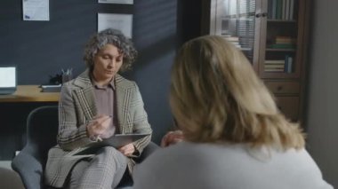 Yetişkin beyaz psikoterapistin tanınmayan erkek hastaya bir şey açıklarken seçmeli odak noktası.