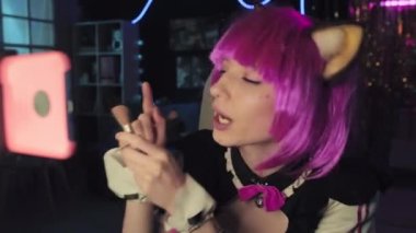 Neko kulaklı hizmetçi kostümü ve pembe peruklu makyaj fırçası görüntülerini akıllı telefon kamerasında görüntülemenin orta boy yakın çekimi.