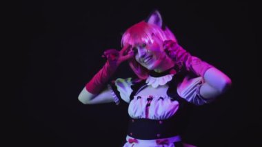 Çekici bir genç kadının orta stüdyo portresi. Neko hizmetçi anime karakteri. Kamerada siyah duvara poz veriyor.