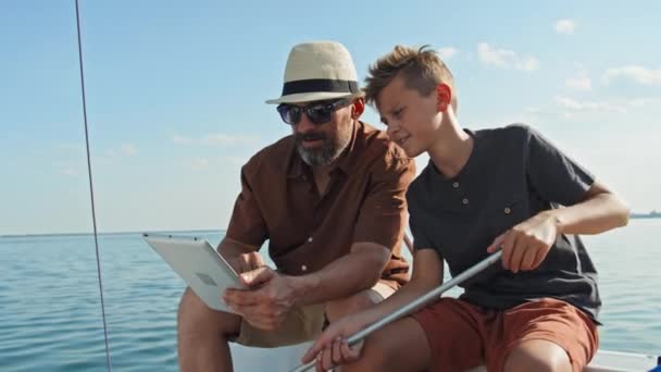 Зрелый Кавказский Мужчина Подросток Сидящие Борту Парусной Яхты Читают Карту — стоковое видео