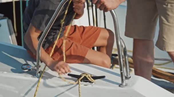 中镜头的现代少年男孩帮助他的父亲为夏天阳光灿烂的一天的航行准备游艇 — 图库视频影像