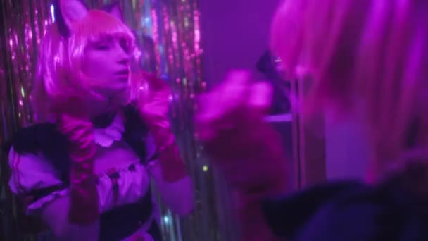穿着动画服装站在镜子前 在霓虹灯下固定假发的年轻女子的选择性聚焦镜头 — 图库视频影像