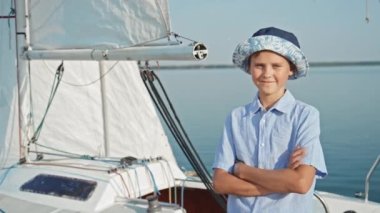 Modern Kafkasyalı gencin orta boy portresi. Yaz günü yatın karşısında duran günlük kıyafetler ve şapka giymiş.