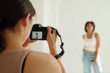 Genç profesyonel fotoğrafçının elindeki fotoğraf makinesine odaklan. Fotokamera ekranında kadın mankenin fotoğrafını çekiyor.
