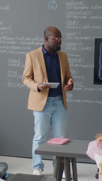 Pionowe Pełne Ujęcie Męskiego Afroamerykańskiego Nauczyciela Dającego Wykład Przed Tablicą — Wideo stockowe