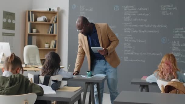 Pełne Ujęcie Męskiego Afroamerykańskiego Nauczyciela Chodzącego Klasie Pomagającego Uczniom Zadaniach — Wideo stockowe