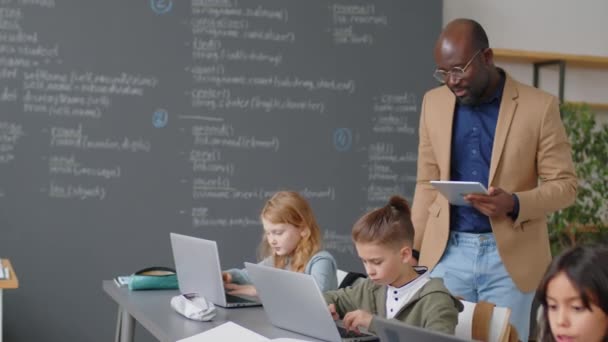 노트북과 아프리카계 미국인 선생님이 하나를 교실에서 책상에 초등학생의 — 비디오