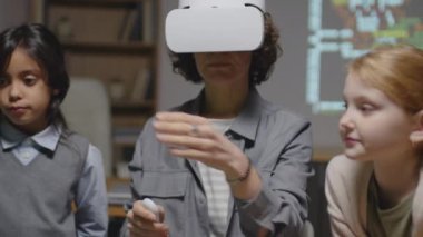 VR gözlüklü beyaz kadın öğretmenin etnik çeşitlilik gösteren bir grup öğrenciye onu dinlerken orta boy bir fotoğrafı.