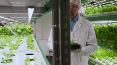 Tıbbi üniformalı üst düzey bir laboratuar çalışanının dikey standa gelip üzerine tıkaç yerleştirdiği orta boy bir fotoğraf.