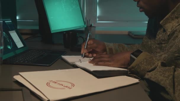 美国黑人男性军事监视官坐在办公室的桌子前 看着屏幕 追踪夜间登记的程序 侧视中图 — 图库视频影像