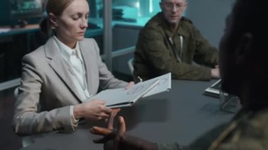 Erkek Afro-Amerikan subayının, Beyaz kadın ve adama gizli belgeler verirken çekilmiş resmi brifingde.
