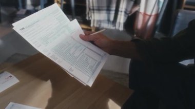 Tanımlanamayan olgun bir adamın evde oturup, bir yığın işe yarar belgeye baktığı, durduğu, vadesi geçmiş faturaları okuduğu ve rakamları kontrol ettiği yakın plan fotoğrafları.