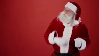 Noel Baba 'nın geleneksel kırmızı takım elbiseli, gri saçlı, sakallı ve kırmızı arka planda coşkuyla dans eden gözlüklü resmi. Şablon, boşluğu kopyala