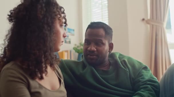タブレット付きの自宅でソファーに座っている若い多民族の妻のミディアムクローズアップショットは アフリカ系アメリカ人の夫への休暇のためのホテルを提案し 旅行の場所を議論 — ストック動画