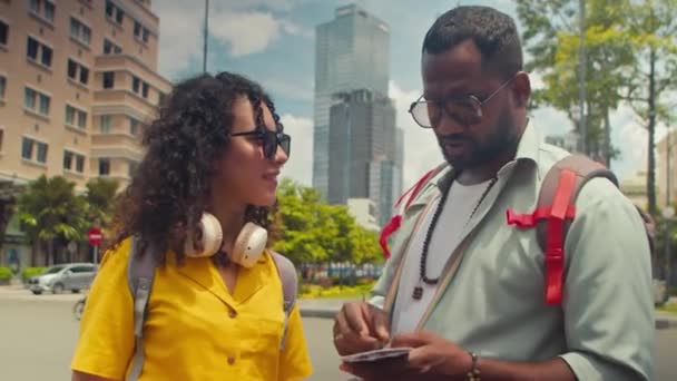 アフリカ系アメリカ人男性とコーカサス人のガールフレンドがサイゴン市内中心部に集結し 観光旅行 小冊子で情報を読んで周りを見回す中 — ストック動画