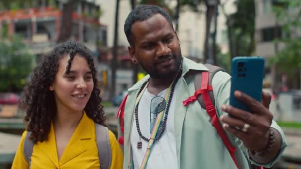 在东南亚城市街道上 一对不同种族的夫妇站在背包里 一边度假一边摆姿势 一边在智能手机上自拍 这对夫妇拍了一张中等特写 — 图库视频影像