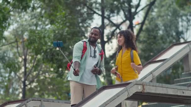 印度丈夫和妻子背负盈亏站在混凝土人行天桥上 用智能手机用自拍棒为旅行博客录下视频 摆出一副笑脸 谈天说地的样子 — 图库视频影像