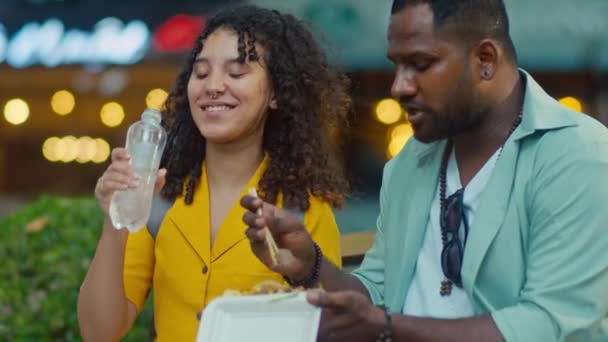 在影片中 非洲裔美国人的丈夫和妻子在国外旅行时 一边吃着美味的异国情调的街头食物 一边交换意见 一边摇头喝水 拍了一张特写镜头 — 图库视频影像