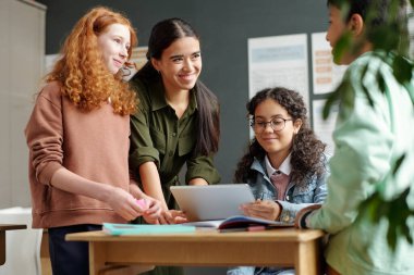 Zeki sınıf arkadaşları ve İngilizce öğretmenleri tartışma sırasında masa başında dururken bazı kuralları açıklayan online video izliyorlar.