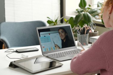 Genç başarılı İngilizce dil bilgisi öğretmeniyle birlikte dizüstü bilgisayar ekranı beyaz tahtaya kuralları gösteriyor ve öğrenene fiillerin türlerini anlatıyor