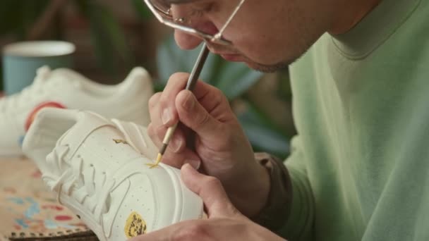 白种人男性时装设计师的特写镜头 白天在室内制作独特的白色运动鞋图案 — 图库视频影像