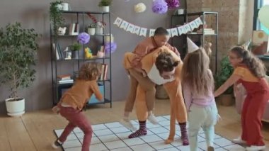 Dört yaramaz çoklu etnik çocuğun doğum günü partisinde kedi kostümlü erkek göstericiyle fiziksel oyunlar oynamaları, etrafta koşuşturmaları, gülmeleri ve çığlık atmaları.