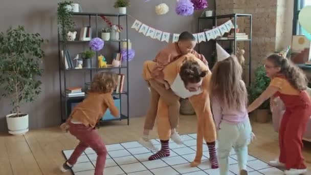 在生日派对上 四个淘气的多种族孩子穿着猫的服装和男艺人玩着体育比赛 跑来跑去 笑着和尖叫着 — 图库视频影像