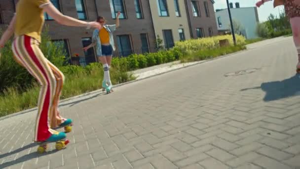 荷兰角度 两个快乐的女孩手牵着手在外面溜冰 一个女孩坐在她们旁边 — 图库视频影像