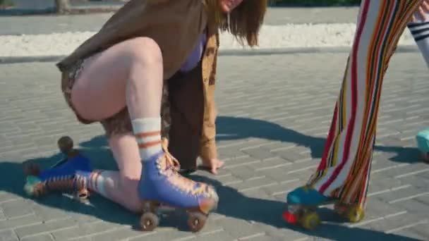 白种人少女帮助女性朋友站起来 拥抱和大笑的倾斜镜头 两人白天都在室外溜冰鞋上 — 图库视频影像
