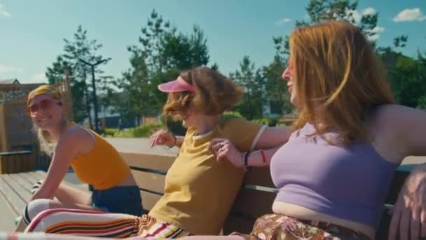三个聪明快乐的少女坐在外面的长椅上 微笑着 谈着话 玩得很开心 — 图库视频影像