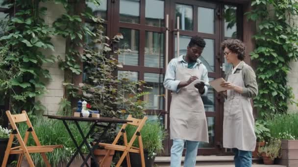 Volledig Beeld Van Twee Verschillende Cafémedewerkers Die Buiten Staan Aantekeningen — Stockvideo