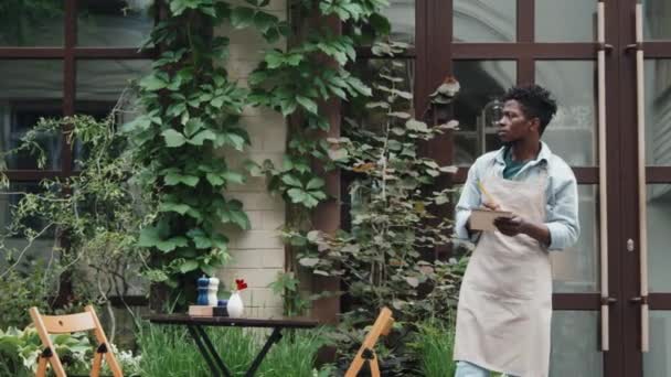 Mittlere Gesamtaufnahme Eines Afroamerikanischen Café Mitarbeiters Der Draußen Steht Nachdenkt — Stockvideo