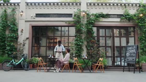 Встановлення Знімка Кавказької Жінки Сидить Столом Відкритому Кафе Афроамериканського Офіціанта — стокове відео