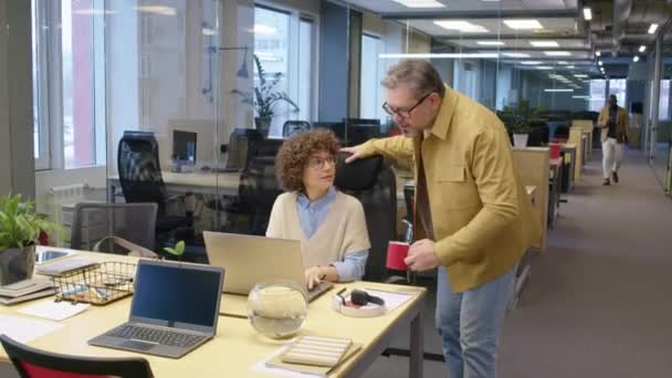 オープンスペースオフィスの廊下に沿って来る赤いカップを持つ男性オフィスマネージャーのフルショット 女性同僚ディスカッション作業の問題 — ストック動画