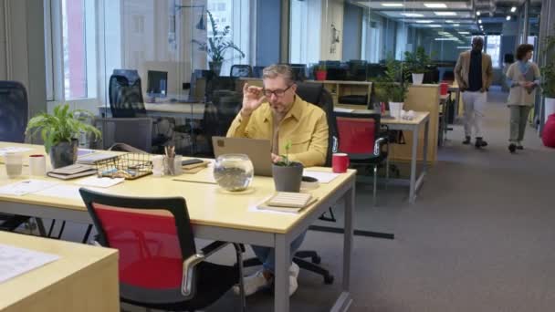 昼間にラップトップの屋内で働くオフィスの机に座っているコーカサス人のマネージャーのショットでズーム — ストック動画