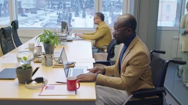 アークショット 男性のアフリカ系アメリカ人のマネージャーは 昼間のオフィスであれば ラップトップで作業する車椅子に座っています — ストック動画