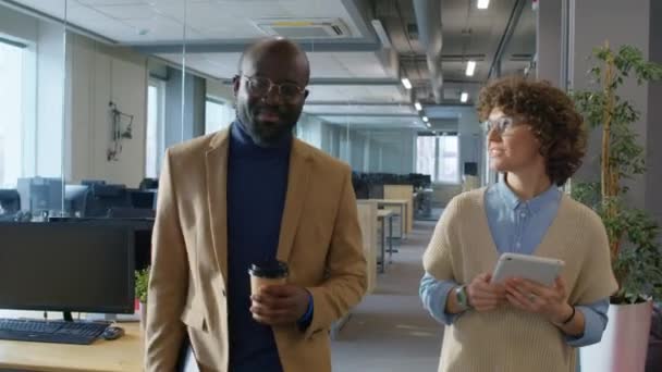 追踪非洲裔美国人和白人男性同事白天在办公室边走边进行热烈交谈的镜头 — 图库视频影像