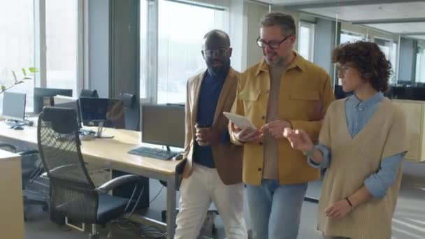 跟踪3名快乐的多种族男女同事在与众多工作单位一起工作时谈论某件事的镜头 — 图库视频影像