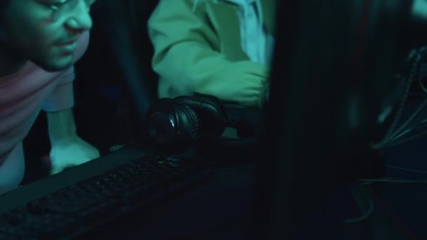 中東の若い男性ゲーマーのミディアムクローズアップショットは サイバークラブの椅子に座って オンラインシューティングゲームに入る前にマイクでヘッドセットを置きます — ストック動画