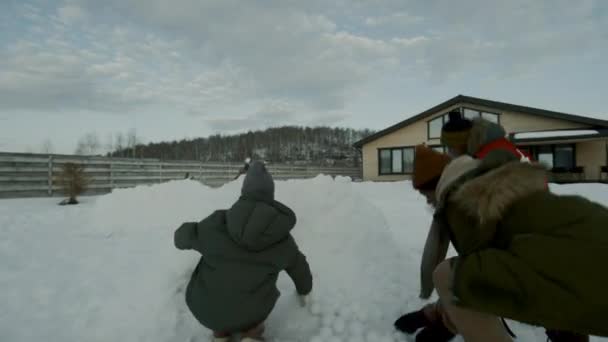三个身穿夹克 头戴礼帽的多民族儿童 在雪球大战中袭击敌人 敌人逃跑 孩子们跳来跳去 击掌高飞 欢呼胜利 — 图库视频影像
