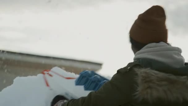 冬日里 穿着皮夹克 头戴暖帽的年轻黑人女孩躲藏在雪墙后面 手持玩具枪 站起来向敌人的要塞发射雪球 在户外玩耍 — 图库视频影像
