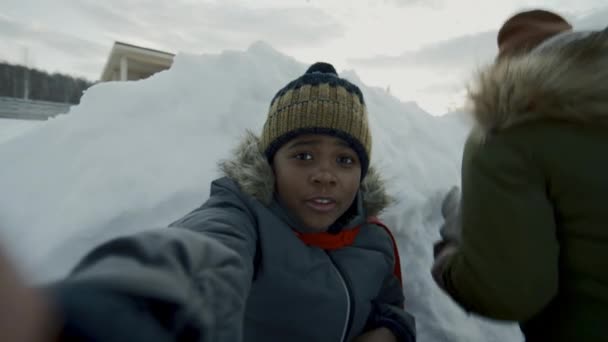 9歳のアフリカ系アメリカ人の兄弟と10代の妹が雪のバリケードの後ろで歌い 友人とスノーボールの戦争をしたり 男の子が話したり 楽しいソーシャルネットワークビデオを録画したり — ストック動画
